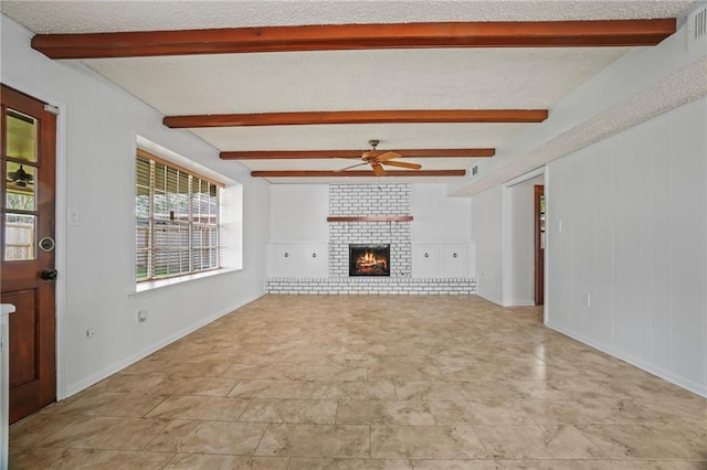 unfurnished living room featuring a textured ceiling, beam ceiling, ceiling fan, and a brick fireplace