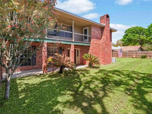 rear view of property with a balcony, a yard, and a patio