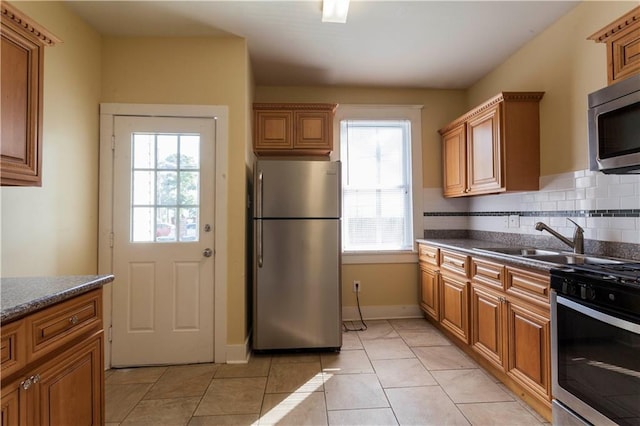 kitchen featuring plenty of natural light, light tile patterned floors, appliances with stainless steel finishes, and tasteful backsplash