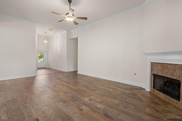 unfurnished living room with hardwood / wood-style flooring, ceiling fan, ornamental molding, and a tile fireplace