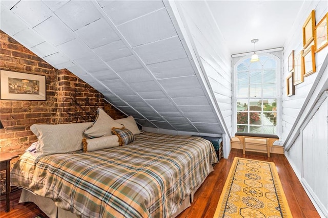 bedroom featuring brick wall, dark hardwood / wood-style floors, and lofted ceiling