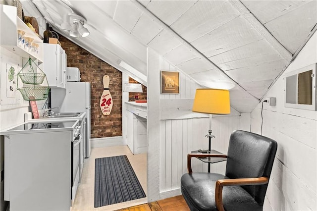 kitchen with lofted ceiling, wooden walls, white cabinetry, and brick wall