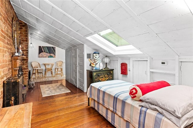 bedroom featuring lofted ceiling with skylight and hardwood / wood-style floors