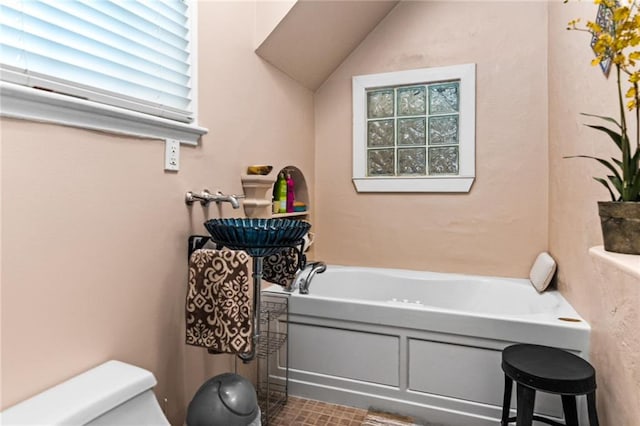 bathroom featuring lofted ceiling, a bathtub, and toilet