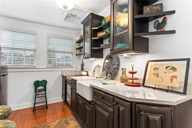 kitchen featuring sink, light stone counters, dark hardwood / wood-style floors, and dark brown cabinets