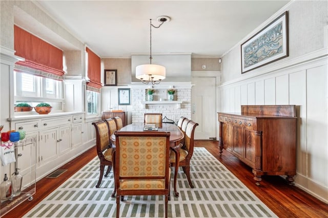 dining space with crown molding, dark wood-type flooring, and a fireplace