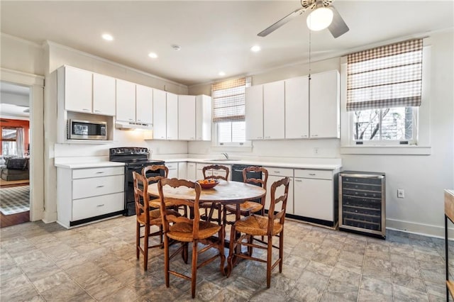 kitchen featuring white cabinets, electric stove, stainless steel microwave, and beverage cooler