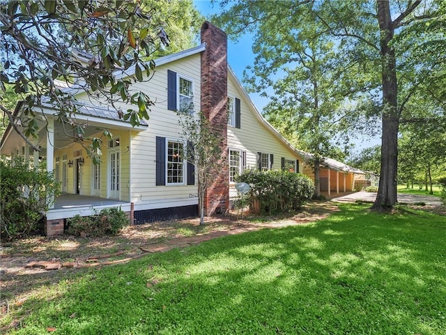 view of side of home featuring covered porch and a lawn