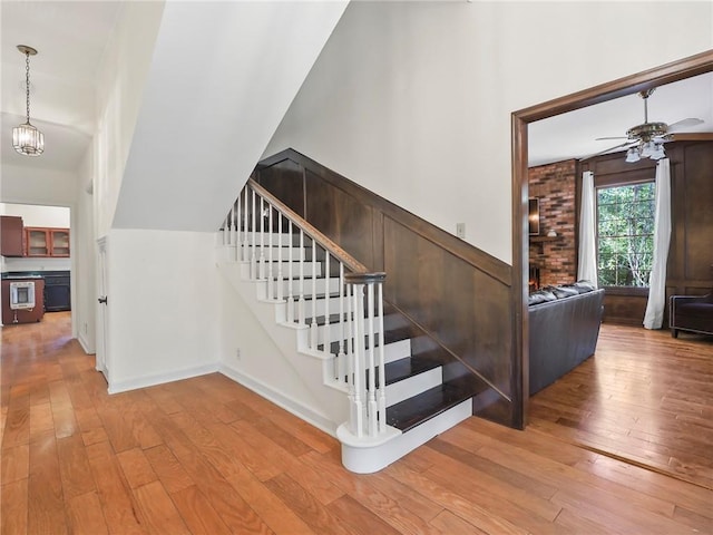 staircase featuring ceiling fan with notable chandelier and hardwood / wood-style flooring