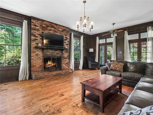 living room with a healthy amount of sunlight, wooden walls, french doors, and wood-type flooring