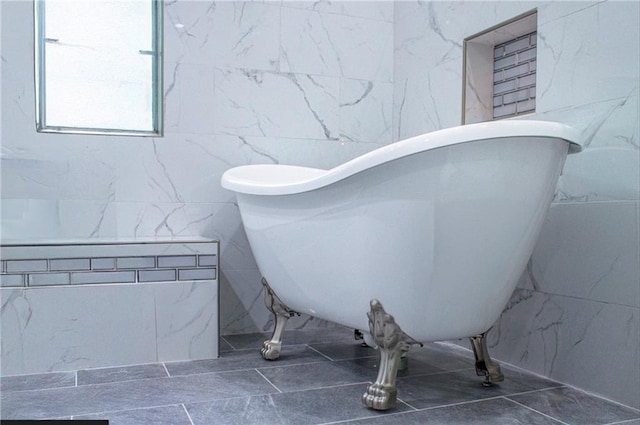 bathroom featuring a washtub and tile walls