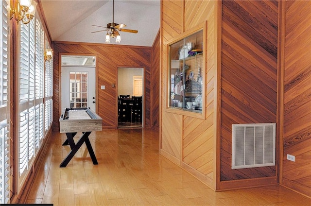 corridor featuring wooden walls, vaulted ceiling, and wood-type flooring