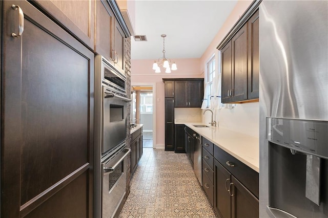 kitchen featuring hanging light fixtures, sink, a notable chandelier, dark brown cabinetry, and stainless steel appliances