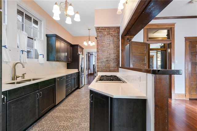 kitchen with appliances with stainless steel finishes, sink, hanging light fixtures, and wood-type flooring