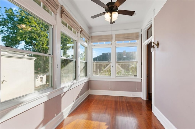 unfurnished sunroom featuring a mountain view, plenty of natural light, and ceiling fan