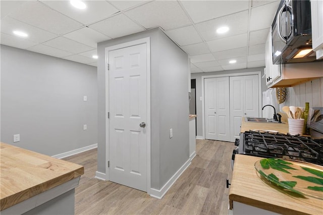 kitchen featuring a paneled ceiling, sink, and light wood-type flooring