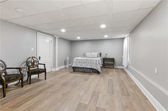 bedroom with a drop ceiling and light wood-type flooring