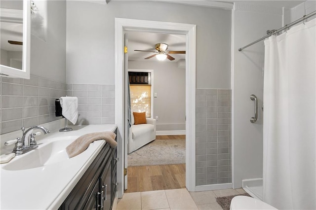 bathroom featuring ceiling fan, wood-type flooring, tile walls, vanity, and a shower with shower curtain