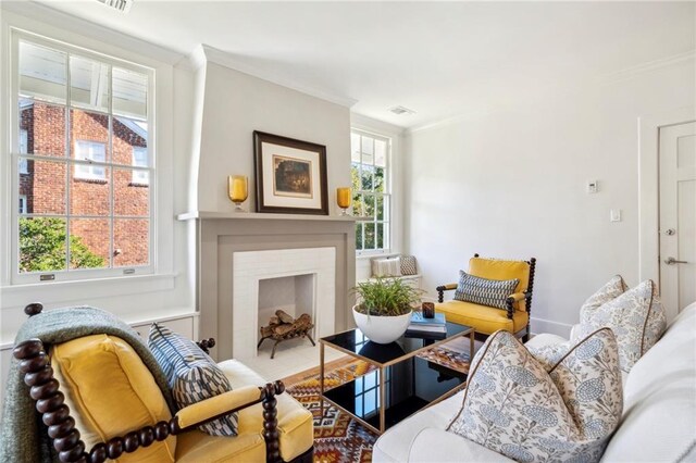 living room with ornamental molding and a fireplace with flush hearth