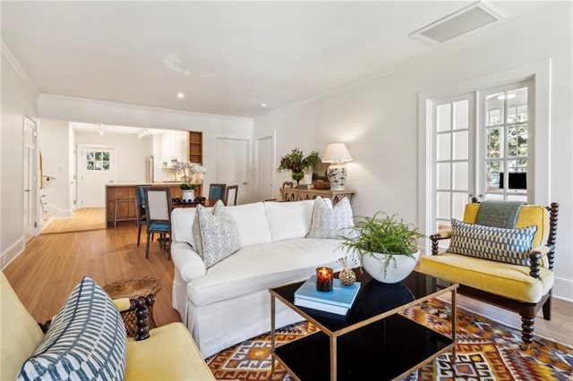 living room with attic access, light wood finished floors, recessed lighting, baseboards, and ornamental molding