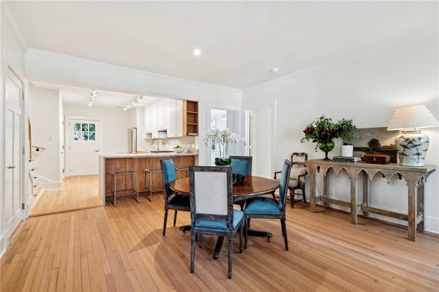 dining area featuring crown molding, baseboards, and light wood-type flooring
