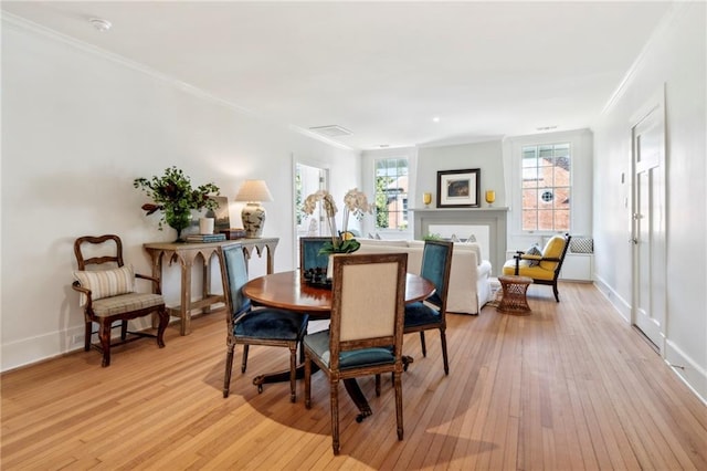 dining room featuring ornamental molding, light wood-style flooring, and baseboards