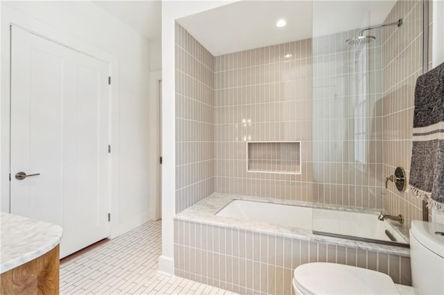 bathroom with tile patterned floors, baseboards, tiled shower / bath combo, and toilet