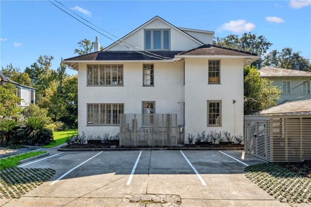 rear view of property featuring uncovered parking and stucco siding