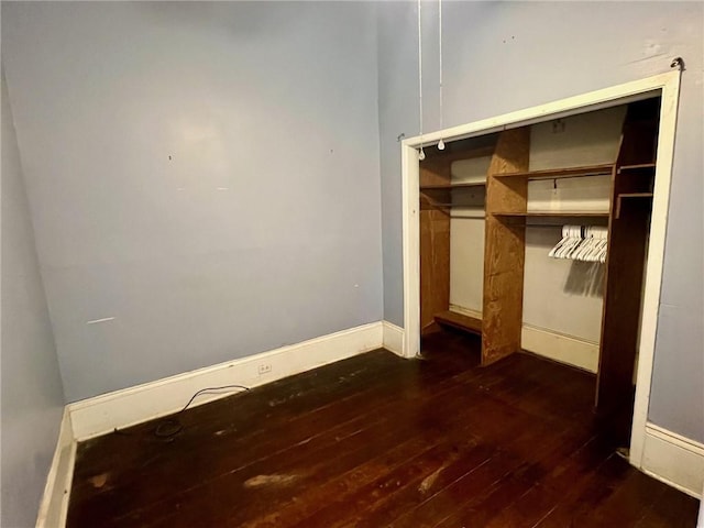 unfurnished bedroom with dark hardwood / wood-style floors and a closet