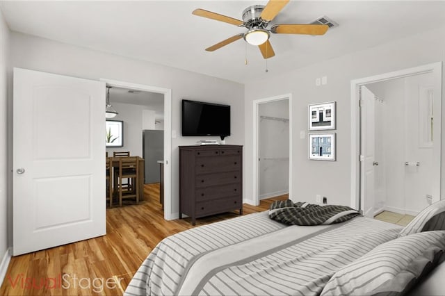 bedroom featuring connected bathroom, a spacious closet, light hardwood / wood-style flooring, a closet, and ceiling fan