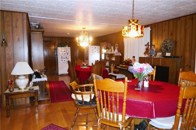 dining area featuring a notable chandelier, light wood-type flooring, and wood walls