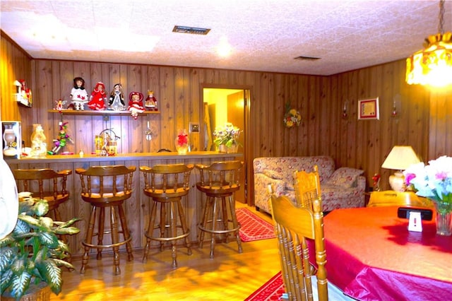 bar featuring hardwood / wood-style flooring and wood walls