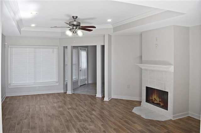 unfurnished living room featuring crown molding, wood-type flooring, a tile fireplace, and ceiling fan