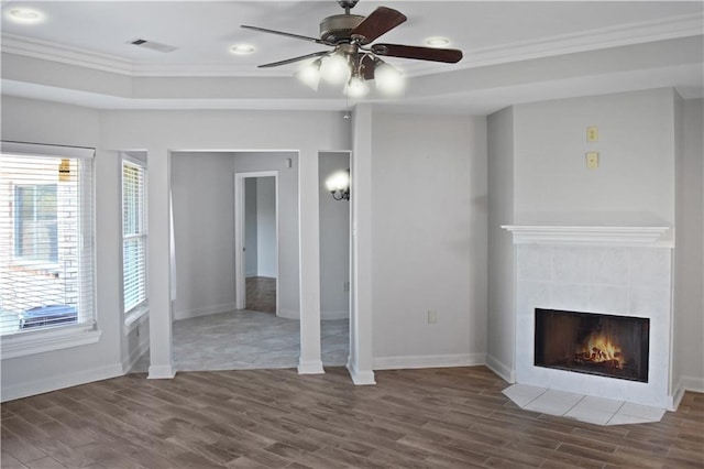 unfurnished living room with dark hardwood / wood-style flooring, crown molding, a tile fireplace, and ceiling fan