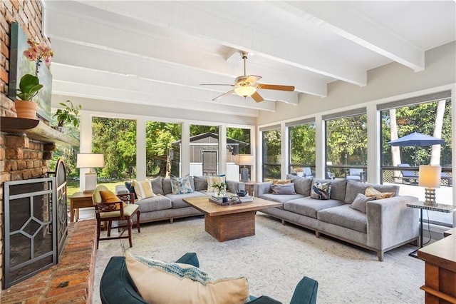 sunroom / solarium with beamed ceiling, ceiling fan, and a fireplace