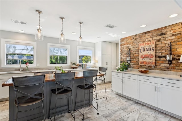 kitchen featuring a kitchen island, pendant lighting, sink, and white cabinets