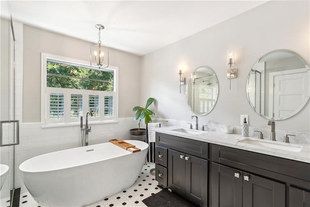 bathroom with tile walls, vanity, independent shower and bath, an inviting chandelier, and tile patterned flooring