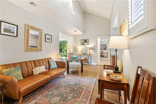 living room with high vaulted ceiling and light wood-type flooring