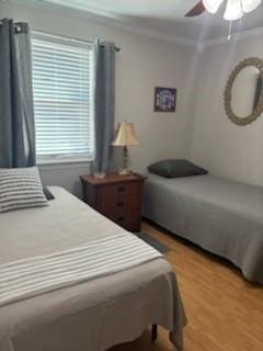 bedroom with crown molding, hardwood / wood-style flooring, and ceiling fan