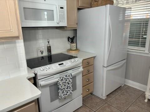 kitchen with decorative backsplash, light tile patterned floors, and white appliances