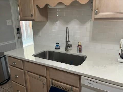 kitchen with dishwasher, light stone countertops, sink, and backsplash