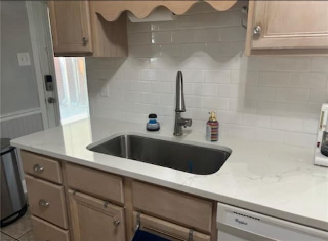 kitchen featuring light stone countertops, tasteful backsplash, white dishwasher, and sink