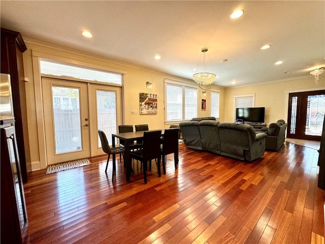 dining space with dark wood-type flooring, ornamental molding, a chandelier, and plenty of natural light