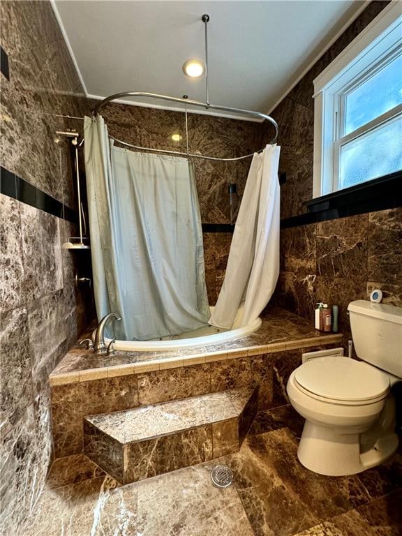 bathroom with tile walls, shower / bath combination with curtain, and toilet