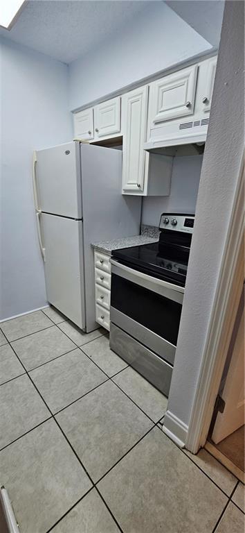 4218 Hessmer Ave Unit 112, Metairie, LA 70002 - kitchen with stainless steel range with electric cooktop, under cabinet range hood, white cabinetry, and light tile patterned flooring