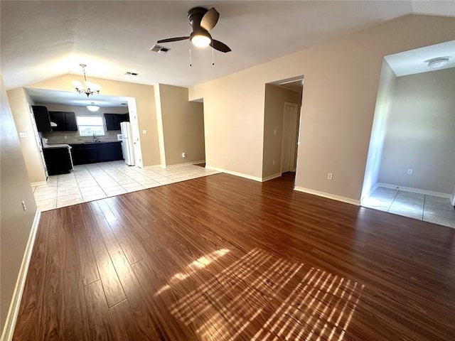 unfurnished living room with vaulted ceiling, sink, wood-type flooring, and ceiling fan with notable chandelier