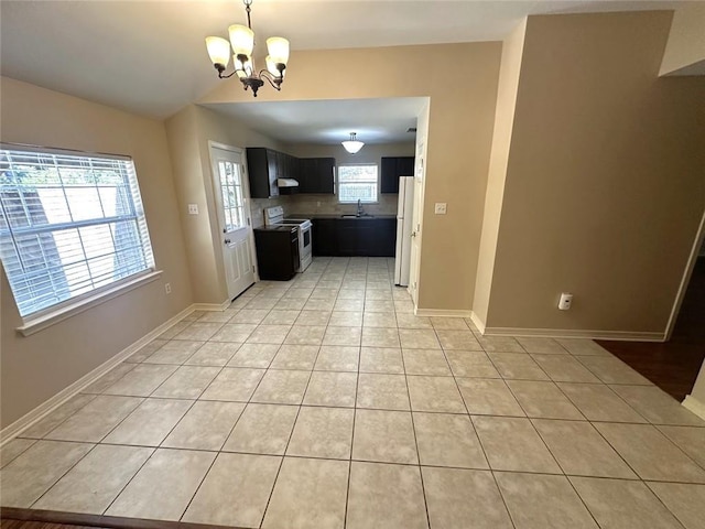 kitchen featuring vaulted ceiling, sink, a chandelier, light tile patterned floors, and white appliances