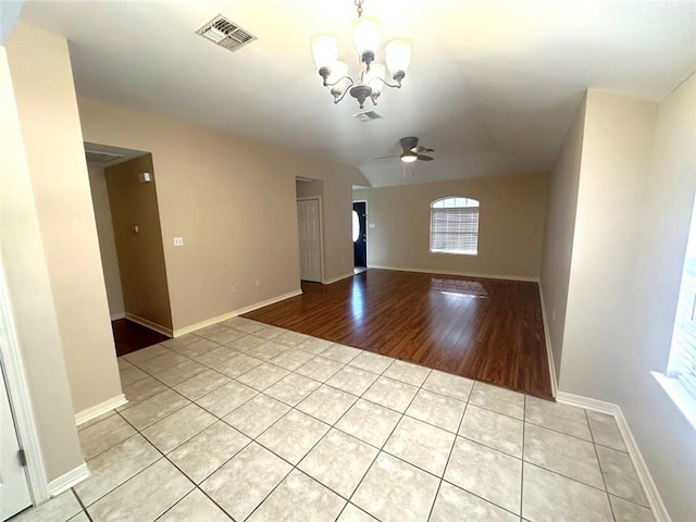 empty room with light tile patterned flooring and ceiling fan with notable chandelier