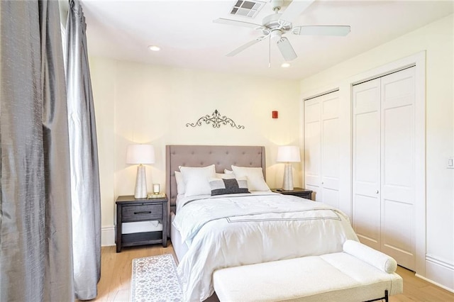 bedroom featuring ceiling fan, multiple closets, and light wood-type flooring