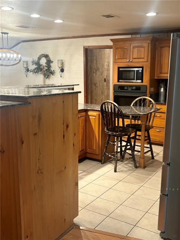 kitchen featuring light tile patterned flooring, appliances with stainless steel finishes, and decorative light fixtures